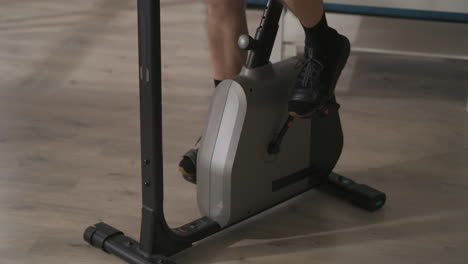 male-feet-are-spinning-pedals-during-training-on-stationary-bike-closeup-shot-healthy-lifestyle-and-fitness-at-home-or-gym